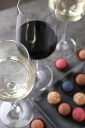 Photo of Tasty wine in glasses and truffle bonbons on grey table, above view