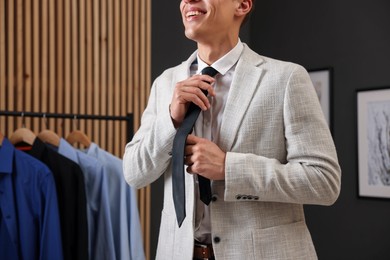 Photo of Man tying stylish necktie at home, closeup