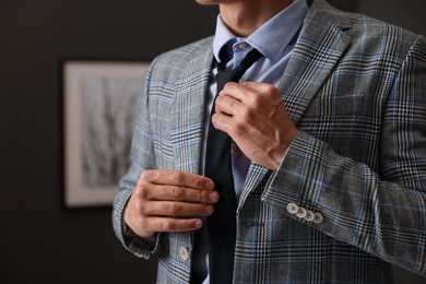 Photo of Man tying stylish necktie at home, closeup