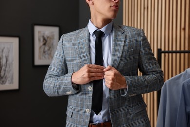 Photo of Man tying stylish necktie at home, closeup