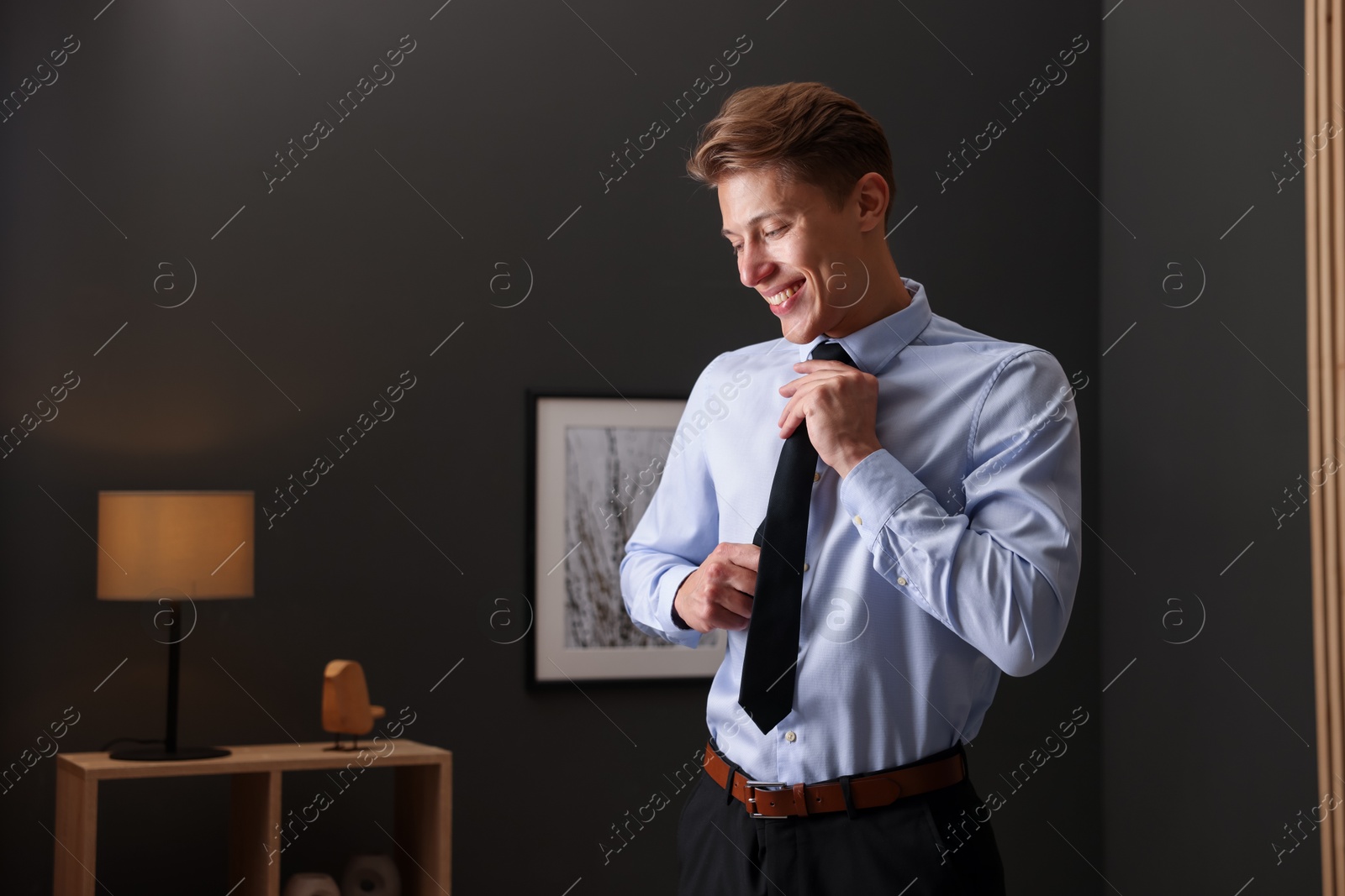 Man tying stylish black necktie at home Photo of Man tying stylish black necktie at home