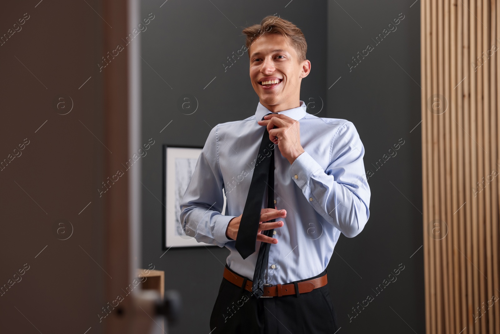 Man tying stylish black necktie at home Photo of Man tying stylish black necktie at home