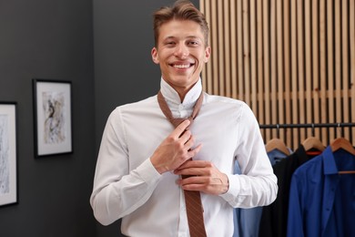 Photo of Man tying stylish brown necktie at home