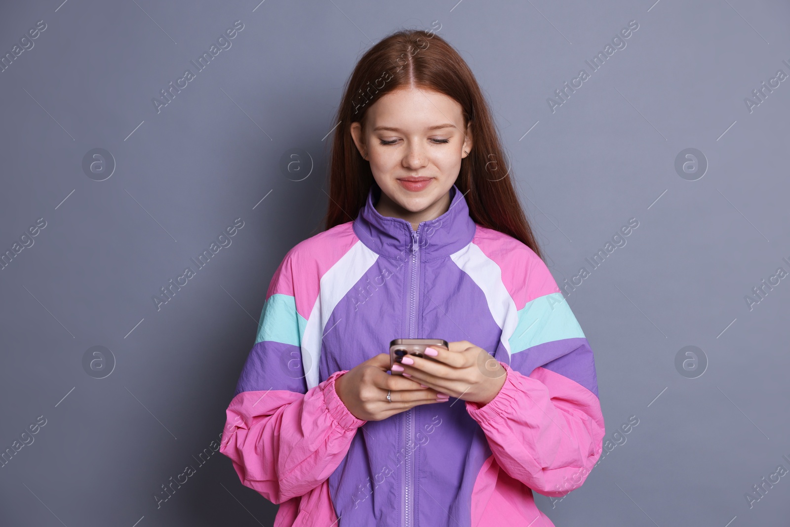 Beautiful teenage girl using smartphone on grey background Photo of Beautiful teenage girl using smartphone on grey background