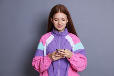 Photo of Beautiful teenage girl using smartphone on grey background