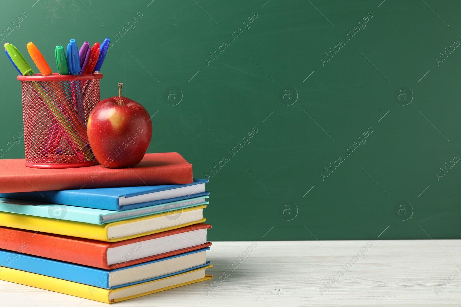 Different school stationery and red apple on white wooden table against blackboard, space for text Photo of Different school stationery and red apple on white wooden table against blackboard, space for text