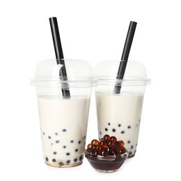 Photo of Tasty milk bubble tea in plastic cups and tapioca pearls isolated on white