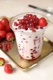 Photo of Tasty milk bubble tea in plastic cup and strawberries on white table, closeup