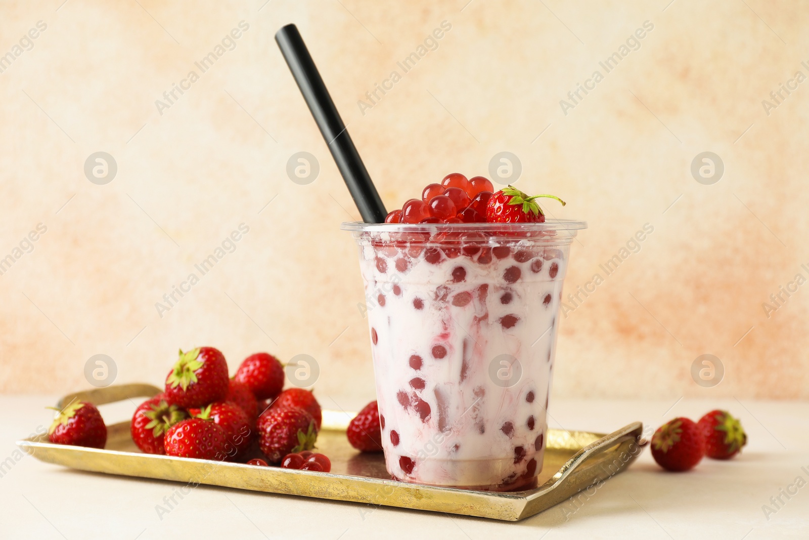 Tasty milk bubble tea in plastic cup and strawberries on white table Photo of Tasty milk bubble tea in plastic cup and strawberries on white table