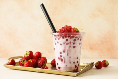 Photo of Tasty milk bubble tea in plastic cup and strawberries on white table