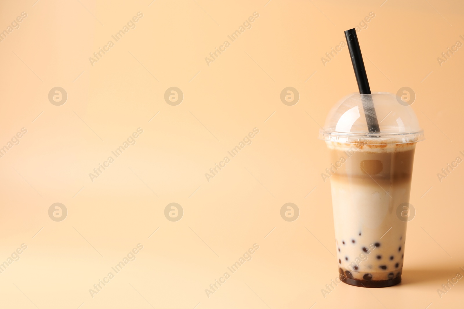 Tasty milk bubble tea in plastic cup on beige background, space for text Photo of Tasty milk bubble tea in plastic cup on beige background, space for text