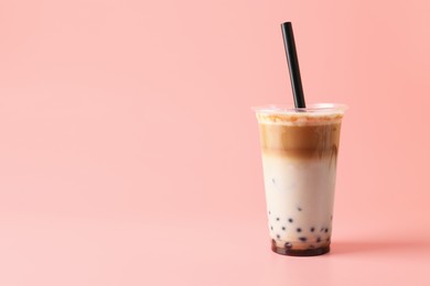 Photo of Tasty milk bubble tea in plastic cup on pink background, space for text