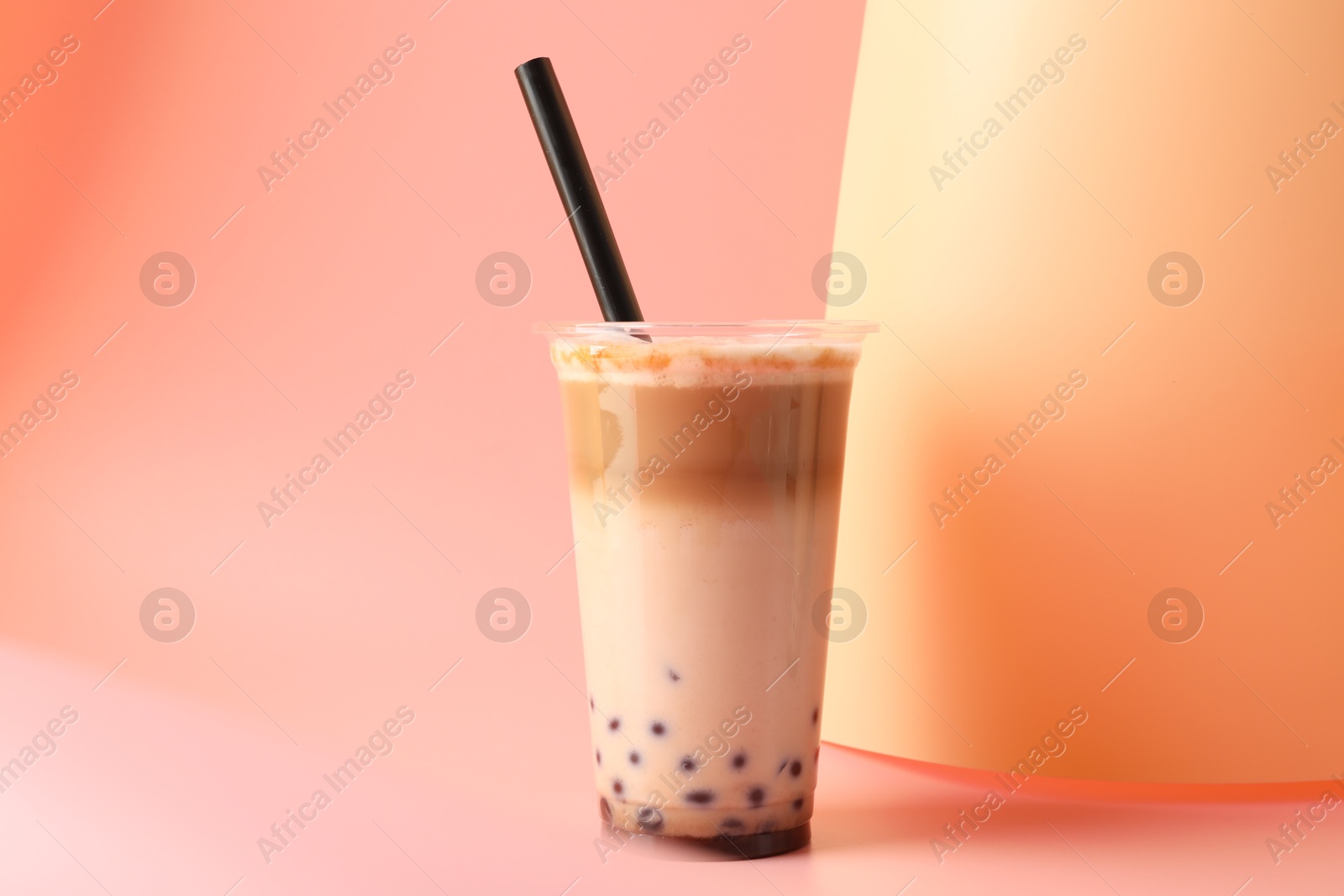 Tasty milk bubble tea in plastic cup on pink background Photo of Tasty milk bubble tea in plastic cup on pink background