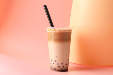 Photo of Tasty milk bubble tea in plastic cup on pink background
