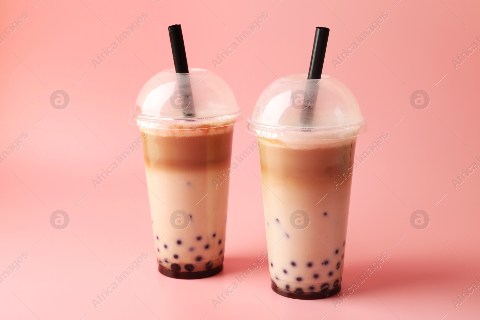 Tasty milk bubble tea in plastic cups on pink background Photo of Tasty milk bubble tea in plastic cups on pink background
