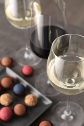 Photo of Tasty wine in glasses and truffle bonbons on grey table, above view