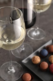 Photo of Tasty wine in glasses and truffle bonbons on grey table, closeup
