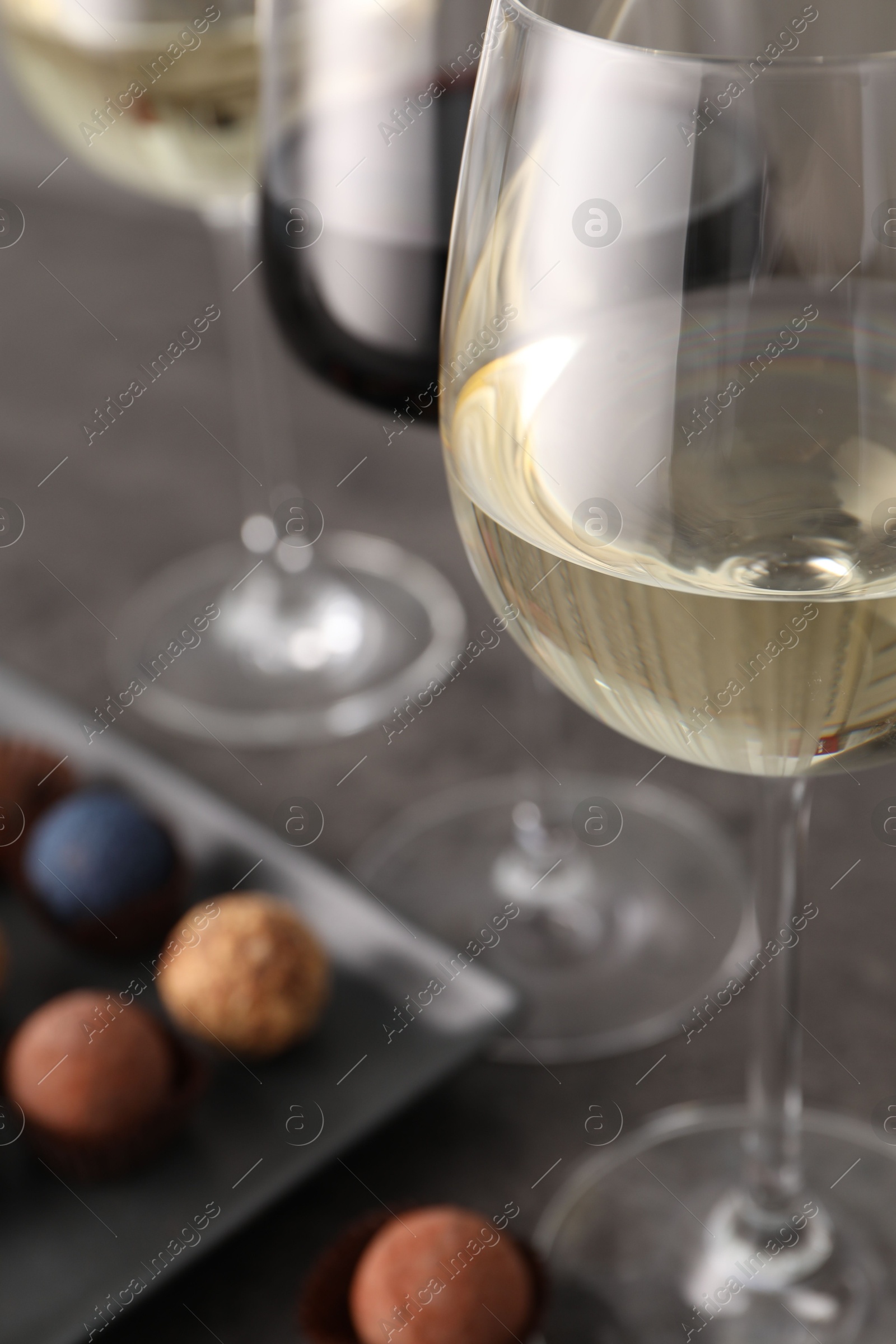 Tasty wine in glasses and truffle bonbons on grey table, closeup Photo of Tasty wine in glasses and truffle bonbons on grey table, closeup