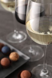 Photo of Tasty wine in glasses and truffle bonbons on grey table, closeup