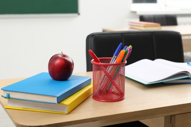 Photo of Different school stationery and red apple on wooden table indoors