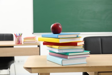Photo of Different books and red apple on wooden table indoors
