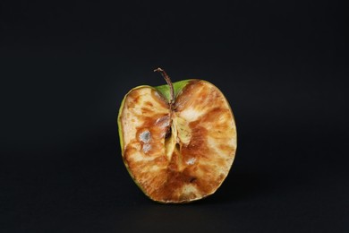 Photo of Half of spoiled apple on black background