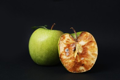 Photo of Spoiled apple and good ones on black background