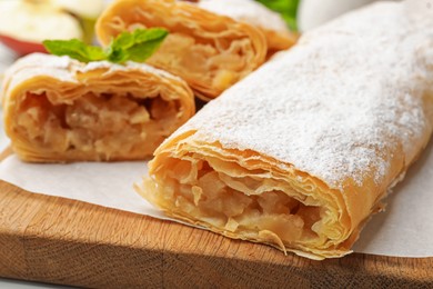 Photo of Tasty apple strudels with powdered sugar and mint on table, closeup
