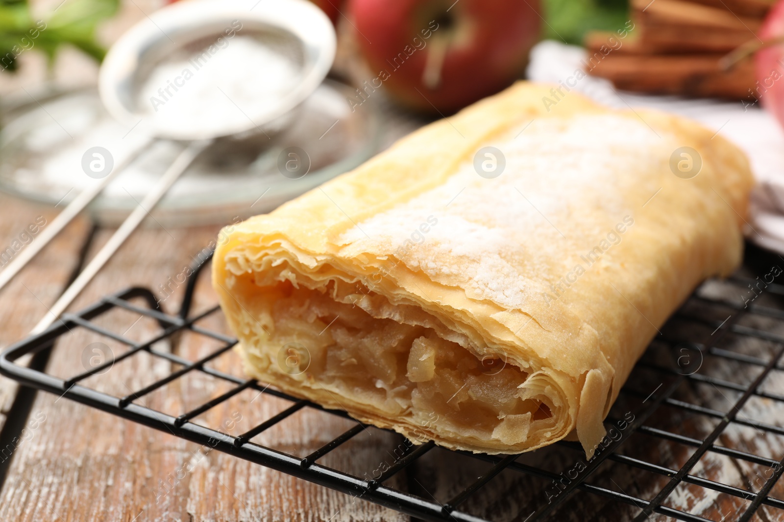Tasty apple strudel with powdered sugar on wooden table, closeup Photo of Tasty apple strudel with powdered sugar on wooden table, closeup