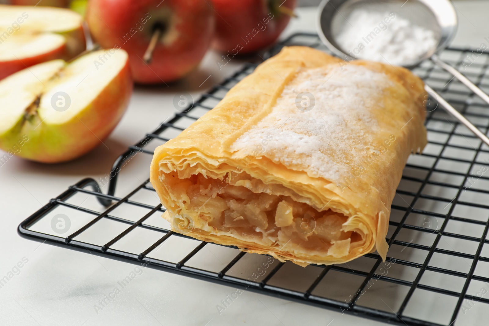 Tasty apple strudel with powdered sugar and fruits on white marble table, closeup Photo of Tasty apple strudel with powdered sugar and fruits on white marble table, closeup