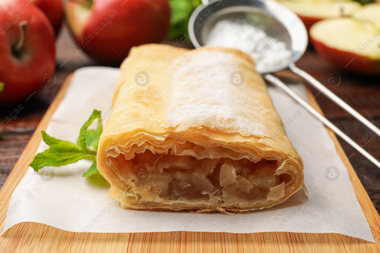 Tasty apple strudel with powdered sugar, mint and fruits on table, closeup Photo of Tasty apple strudel with powdered sugar, mint and fruits on table, closeup