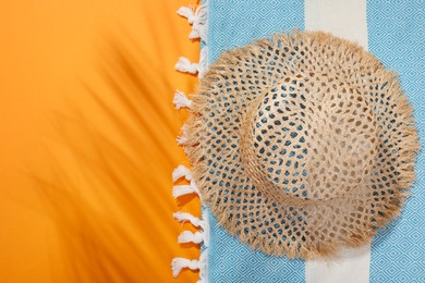 Photo of Hat and beach towel on orange background, top view. Space for text