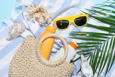 Photo of Beach accessories, sea shells and palm leaf on light blue background, flat lay