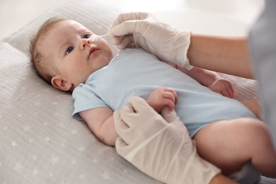 Photo of Pediatrician examining baby at table in clinic, closeup