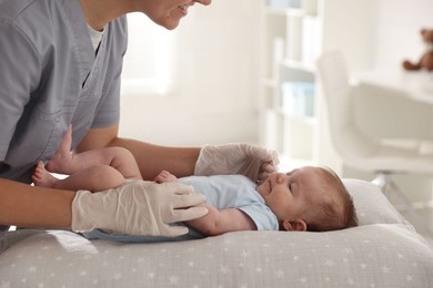 Photo of Pediatrician examining baby at table in clinic, closeup