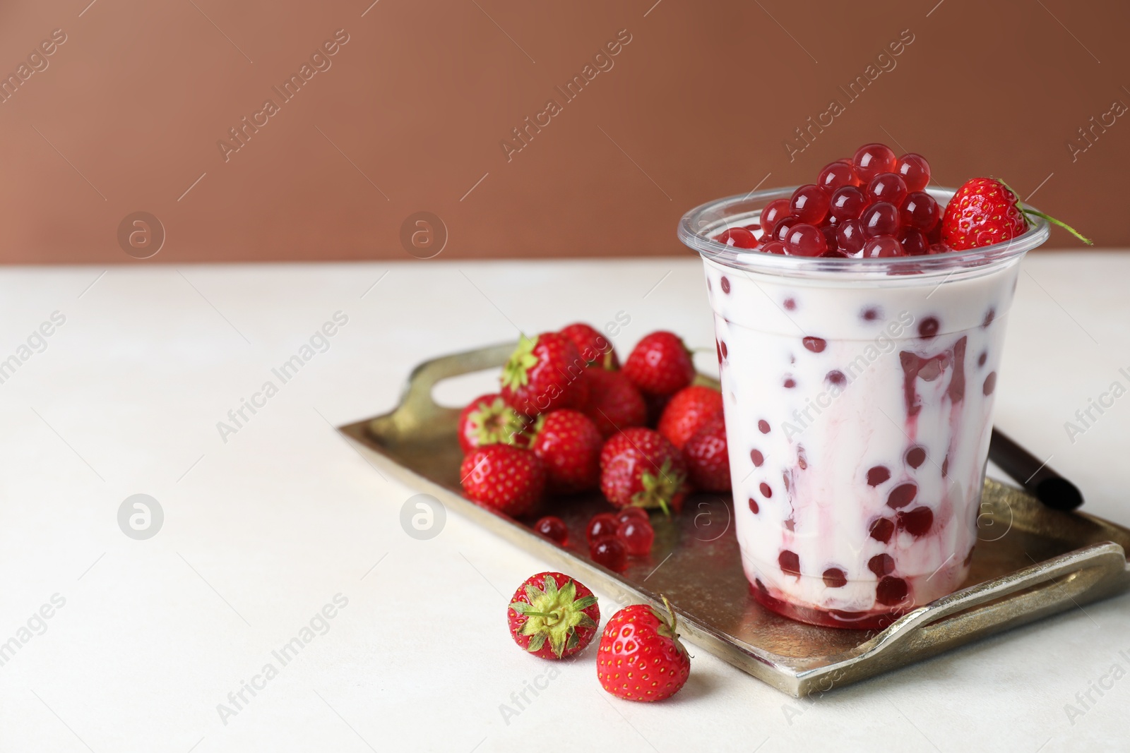 Tasty milk bubble tea in plastic cup and strawberries on white table, closeup. Space for text Photo of Tasty milk bubble tea in plastic cup and strawberries on white table, closeup. Space for text