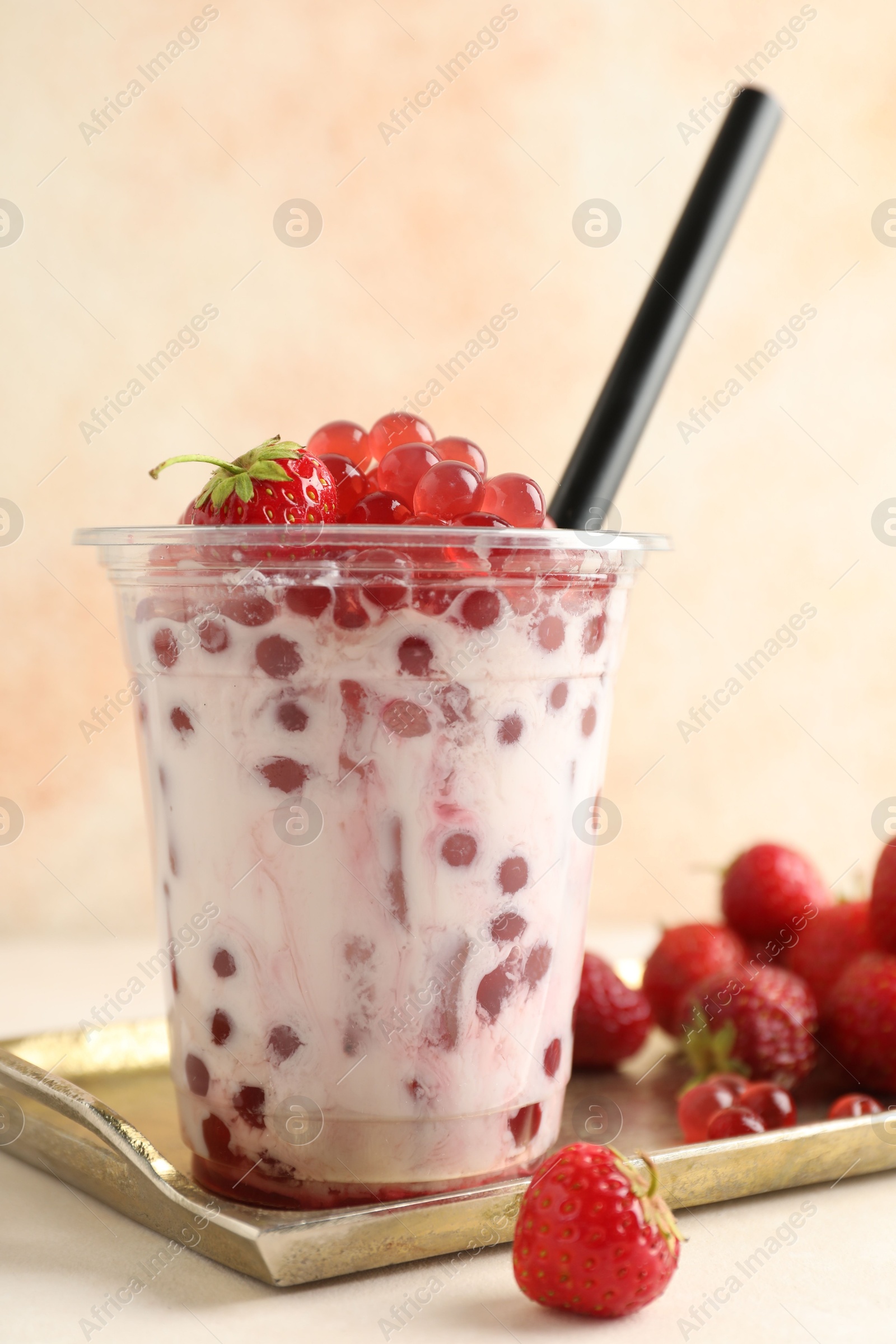 Tasty milk bubble tea in plastic cup and strawberries on white table, closeup Photo of Tasty milk bubble tea in plastic cup and strawberries on white table, closeup