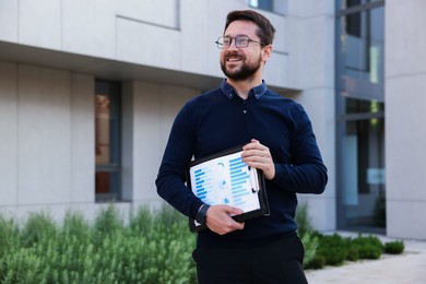 Photo of Happy businessman with clipboard near office building