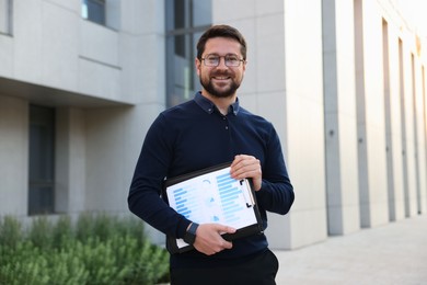 Photo of Happy businessman with clipboard near office building