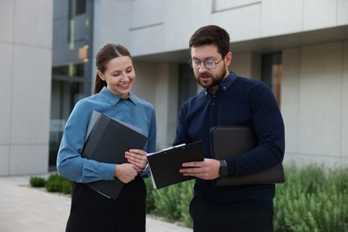 Photo of Happy coworkers discussing something near office building