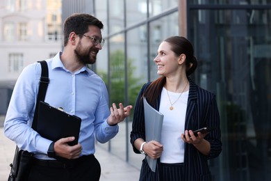 Photo of Happy coworkers discussing something near office building