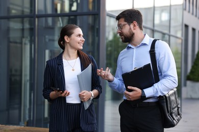 Photo of Happy coworkers discussing something near office building