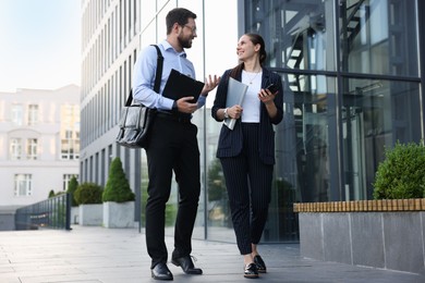Photo of Happy coworkers discussing something near office building