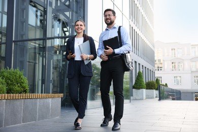 Photo of Happy coworkers discussing something near office building