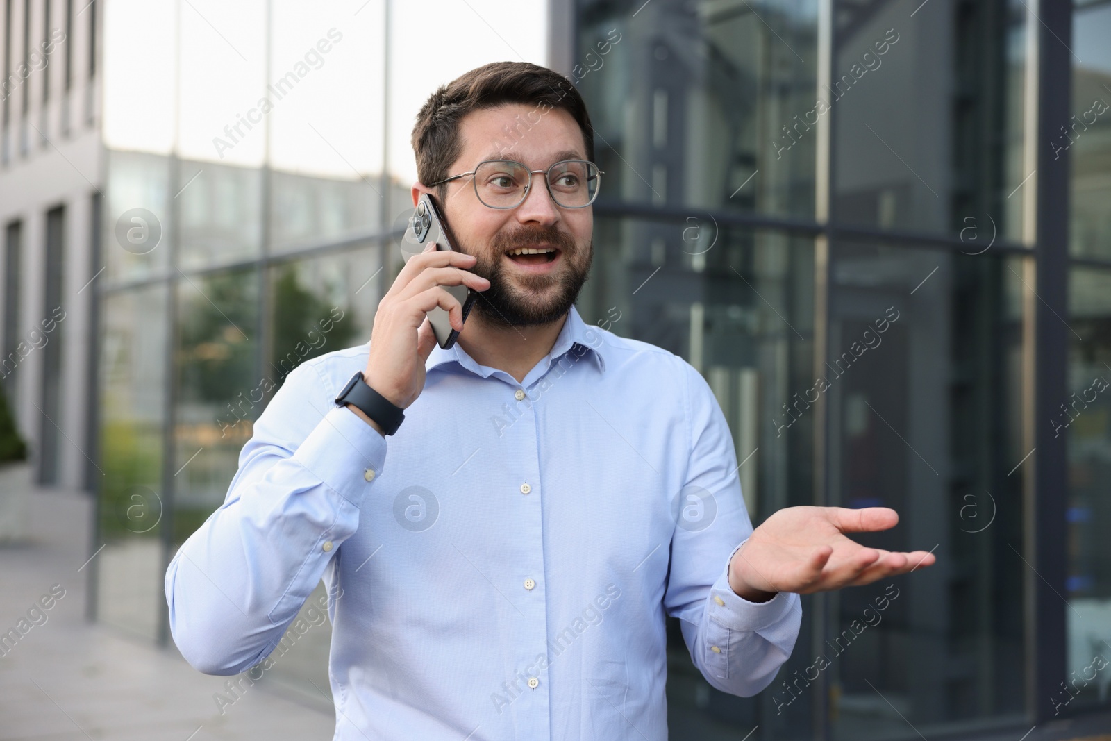 Happy businessman talking on phone near office building Photo of Happy businessman talking on phone near office building