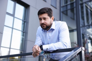 Photo of Tired businessman with glasses outside office building