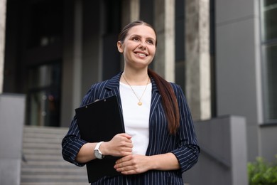Photo of Happy businesswoman with folder near office building