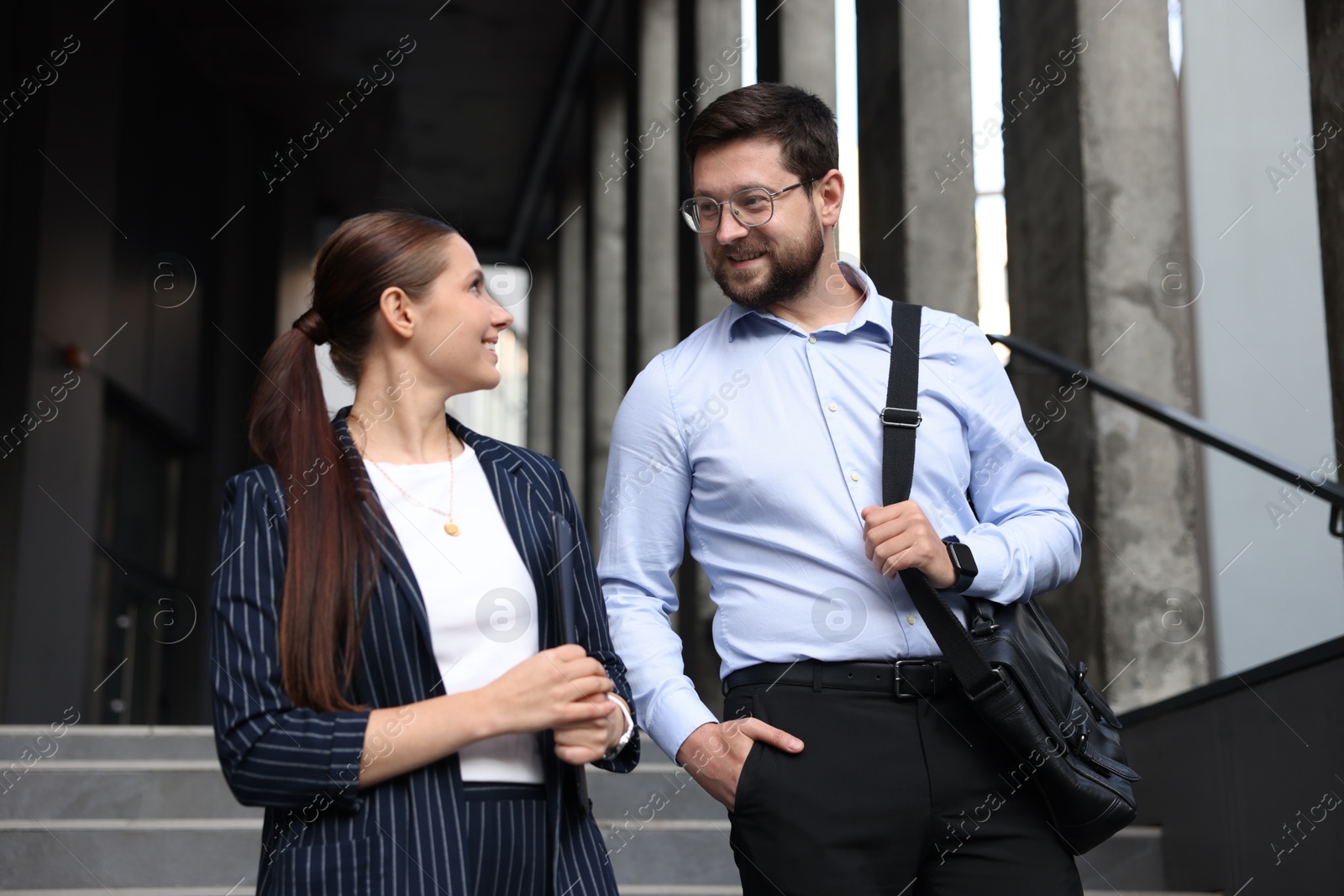 Happy coworkers discussing something near office building Photo of Happy coworkers discussing something near office building