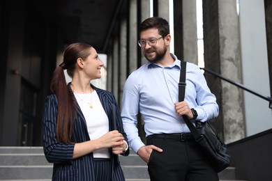Photo of Happy coworkers discussing something near office building