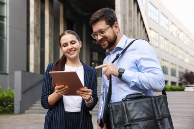 Photo of Happy coworkers with tablet near office building